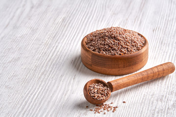 Wall Mural - Psyllium Husk seeds , fiber source , in wooden bowl on white wooden background. Closeup with copy space