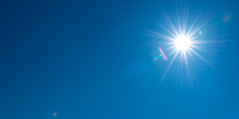 sun, sunbeams against blue sky - cloudless heaven. photography with lense flair effect