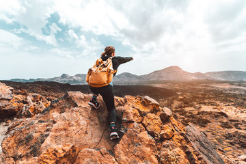 Wall Mural - beautiful hiker woman on the top of the mountain pointing at the sunset valley. girl with backpack t
