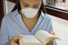 COVID-19 Pandemic Coronavirus Woman Home Isolation Auto Quarantine Wearing Face Mask Reading Book Or Studying Information About Coronavirus Disease 2019. Quarantine Girl Reading Book At Home.