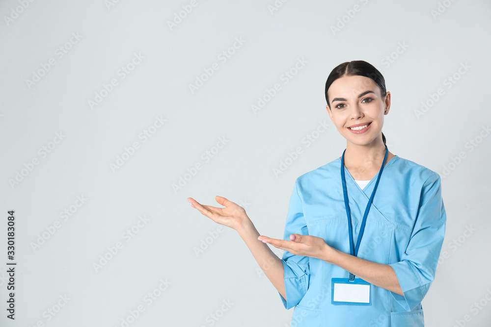 Portrait of young doctor against light background - obrazy, fototapety, plakaty 