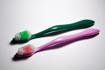 Two toothbrushes green and pink. A pair of personal care products on a white background. Dentistry and dentists. Teeth cleaning.