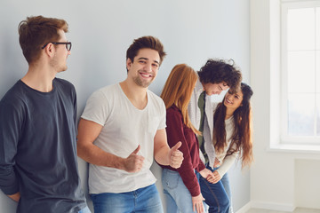 Wall Mural - A group of smiling friends is standing in a bright room with a window.