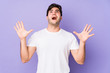 © Asier - Young man isolated on purple background screaming to the sky, looking up, frustrated.