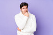 © Asier - Young man isolated on purple background looking sideways with doubtful and skeptical expression.