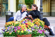 © amarinchenko106 - A young girl is talking to an elderly woman sitting on a bench among flowers.