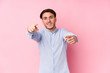 © Asier - Young caucasian man posing in a pink background isolated cheerful smiles pointing to front.