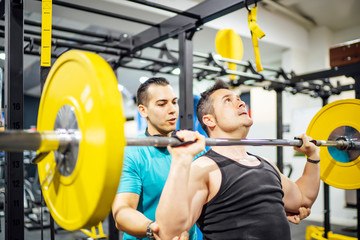 Two men training in gym lifting weights.