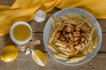 Penne pasta with  chicken in a creamy sauce on a light wooden background.