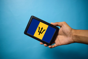 Man holding Smartphone with Flag of Barbados. Barbados Flag on Mobile Screen isolated On Blue Background