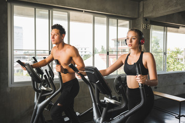 Group of people at the gym exercising on the cross trainer machine. Young fitness men and women doing cardio workout program for beginner.