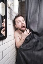 Frightened Man Peeks Out From Behind The Curtains, In The Shower, He Is Shocked, Opened Mouth And Makes Big Eyes.