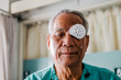 patient covering eye with protective shield after eyes cataract surgery in hospital