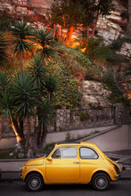 Yellow Little Retro Car On A Background Of Green Palm Trees In Italy, Sorrento. Concept: A Trip On A Vintage Car Along The Amalfi Coast Of Italy.