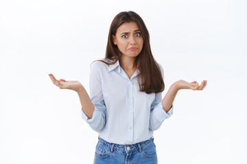 Wall Mural - Perplexed silly young worried woman dont know what to say, have no answer, look embarrassed say sorry and shrugging with hands spread sideways, being clueless and indecisive what do, white background