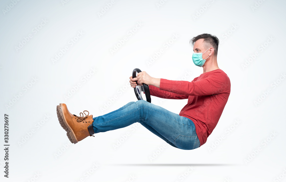 Man in respiratory mask drives a car while holding a steering wheel. Attention virus concept - obrazy, fototapety, plakaty 