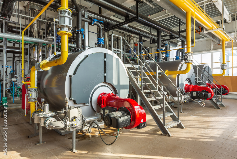 The interior of an industrial boiler room with three large boilers, many pipes, valves and sensors - obrazy, fototapety, plakaty 