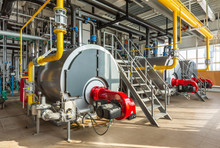 The Interior Of An Industrial Boiler Room With Three Large Boilers, Many Pipes, Valves And Sensors