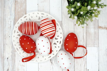 White and red Easter eggs in nest over wooden background