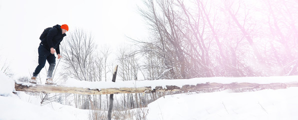 Wall Mural - A man in the winter in the forest. A tourist with a backpack goes through the woods in winter. Winter ascent.