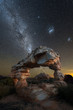 A dramatic vertical night sky landscape photograph of an incredible rock arch, with the Milky Way and Magellanic Clouds in the background, taken in the Cederberg mountains, South Africa.