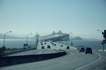 Sticker - Cars riding through The Richmondâ€“San Rafael Bridge surrounded by the sea in California