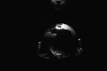 Wall Mural - hands of little girl hold globe sphere map isolated on black background. covid-19 pandemic infection