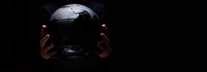 Wall Mural - hands of little girl hold globe sphere map isolated on black background. covid-19 pandemic infection