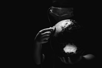Wall Mural - kid hold globe put stethoscope on sphere, face covered in mask on black background. ecological probl
