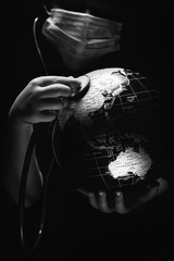 Wall Mural - kid hold globe put stethoscope on sphere, face covered in mask on black background. ecological probl