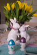 Happy Easter! Piękna dekoracja na wielkanocnym stole z kolorowymi pisankami, zajączkami i świeżymi kwiatami w wazonie