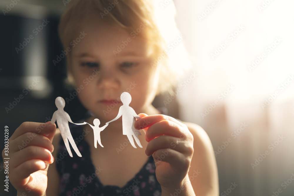 little girl with paper family in hands. concept of divorce, custody and child abuse - obrazy, fototapety, plakaty 