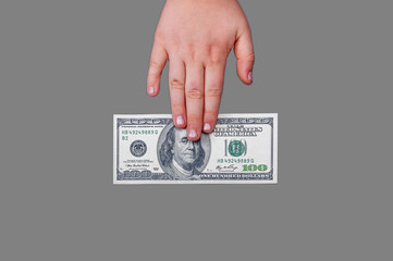 a human hand lies on a banknote of 100 American dollars with a portrait of American President Benjamin Franklinan isolated gray background