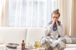 © weyo - Girl sitting on a sofa and sneezing because of cold and fever