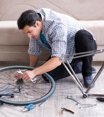 Young man repairing bicycle at home