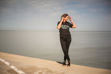 woman posing on waterfront wearing all black with a graphic tee