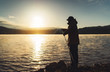 © A_B_C - silhouette fisherman fishing rod at sunrise sunlight, outline man enjoy hobby on evening lake, person catch fish on background night sky, relaxation vacation fishery concept