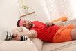 © New Africa - Lazy young man with sport equipment on sofa at home