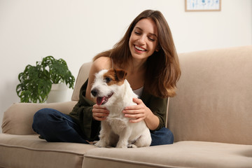 Poster - Young woman with her cute Jack Russell Terrier on sofa at home. Lovely pet