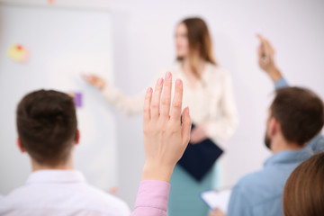 Wall Mural - Woman raising hand to ask question at business training indoors, closeup