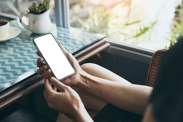 Mockup image blank white screen cell phone.woman hand holding texting using mobile on desk at coffee shop.background empty space for advertise text.people contact marketing business,technology