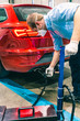 © GaiBru Photo - A technician doing an emission control of a security inspection of a vehicle protected with a mask and gloves to prevent the spread of virus