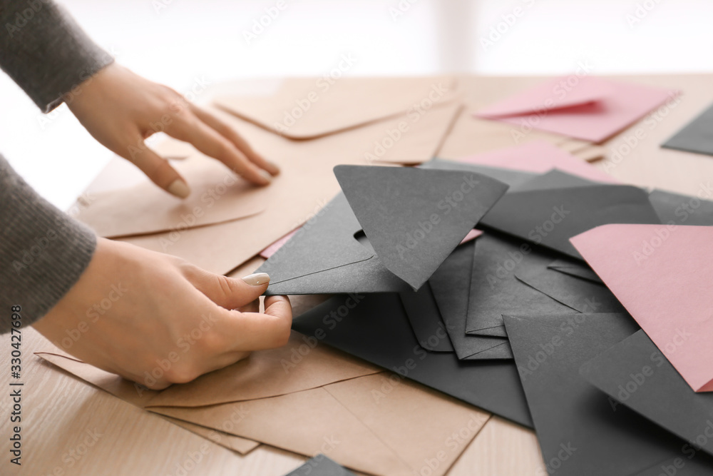Woman with heap of envelopes on table