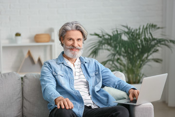 Wall Mural - Stylish elderly man with laptop at home