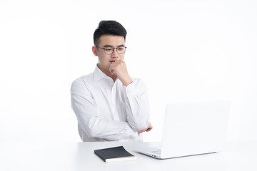 A young Asian man is using his mobile phone and laptop