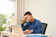 © makistock - Feeling exhausted. Frustrated young beard man massaging his head and keeping eyes closed while sitting at his working place in office