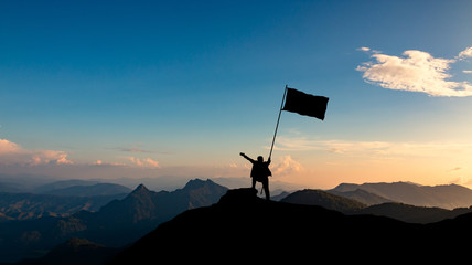 silhouette of businessman with flag on mountain top over sunset sky background, business, success, leadership and achievement concept.