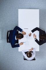 Group of business people and lawyer discussing contract papers sitting at the table, view from above. Businessman is signing document after agreement done