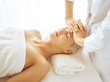 © rogerphoto - Beautiful blonde woman enjoying facial massage with closed eyes. Relaxing treatment in medicine and spa center concepts