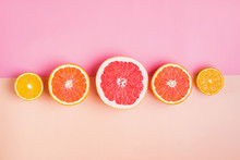 Slices Of Different Citrus Fruits On Pink Background